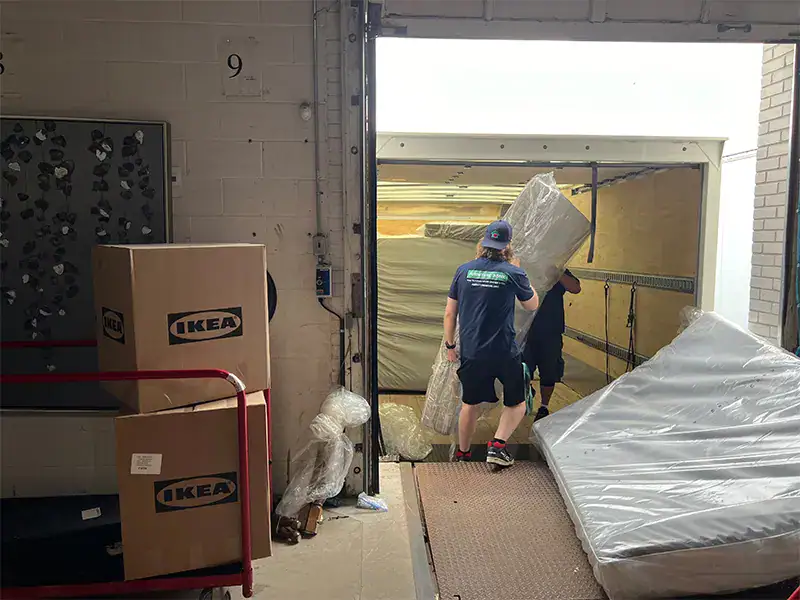 Two crew members unloading furniture from a truck